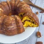 A pecan upside down bundt cake on a white plate with one piece cut out but still on the plate.