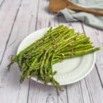 Roasted Asparagus Appetizer on a white plate on a wooden table.