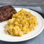 Dutch Oven Macaroni and Cheese on a white plate with a steak on the side.
