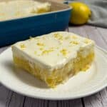 Lemon Layered Jello Dessert on a white plate with a blue casserole dish in the background.